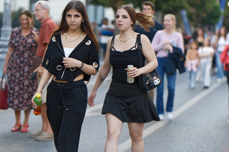 30 - Two young women walking down a city street in casual dark outfits